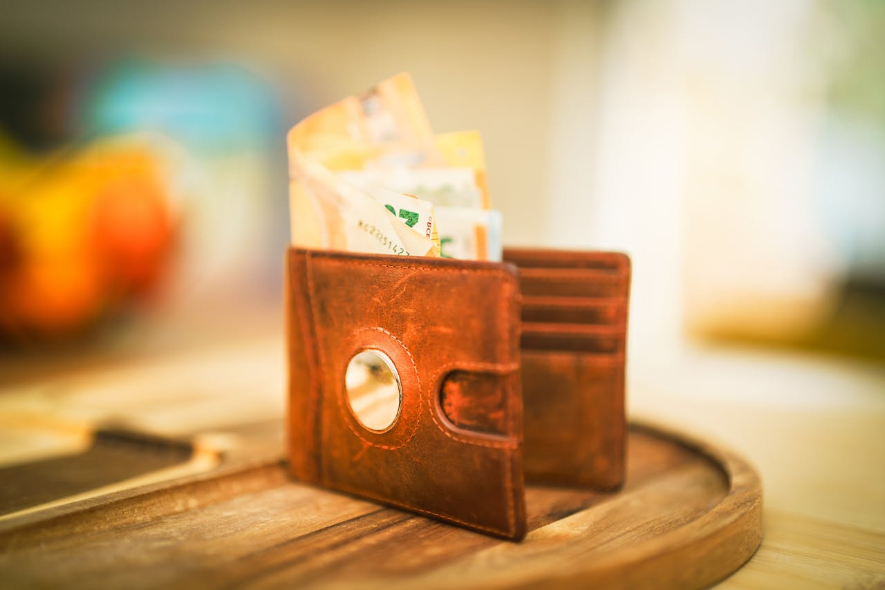 brown-leather-wallet-with-currency-on-wooden-table-30704822